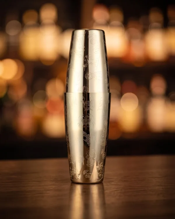 Gold engraved Boston shaker, Hula pattern, on a bar counter