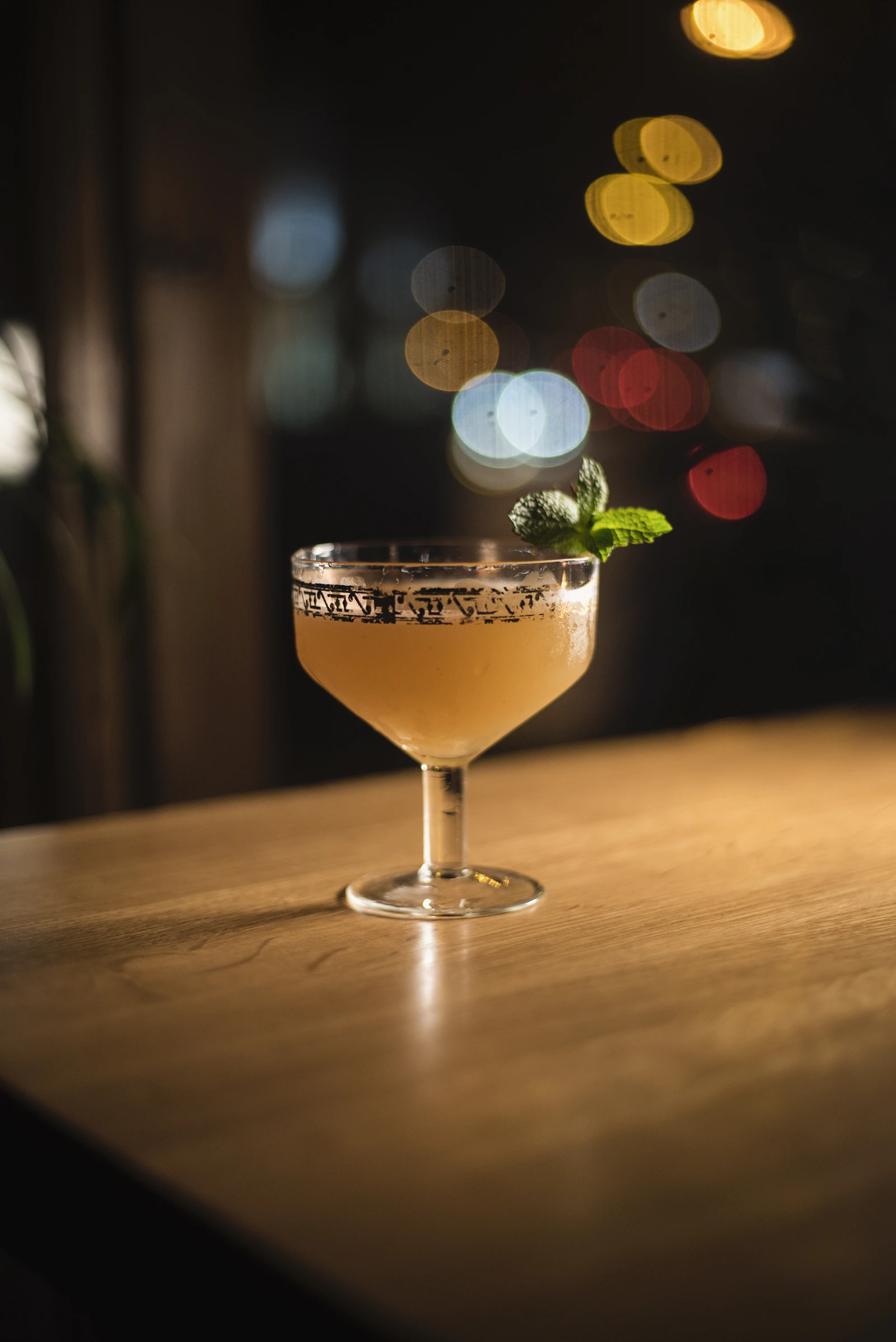 Daiquiri served in an engraved coupe on a wooden bar counter, under soft lighting