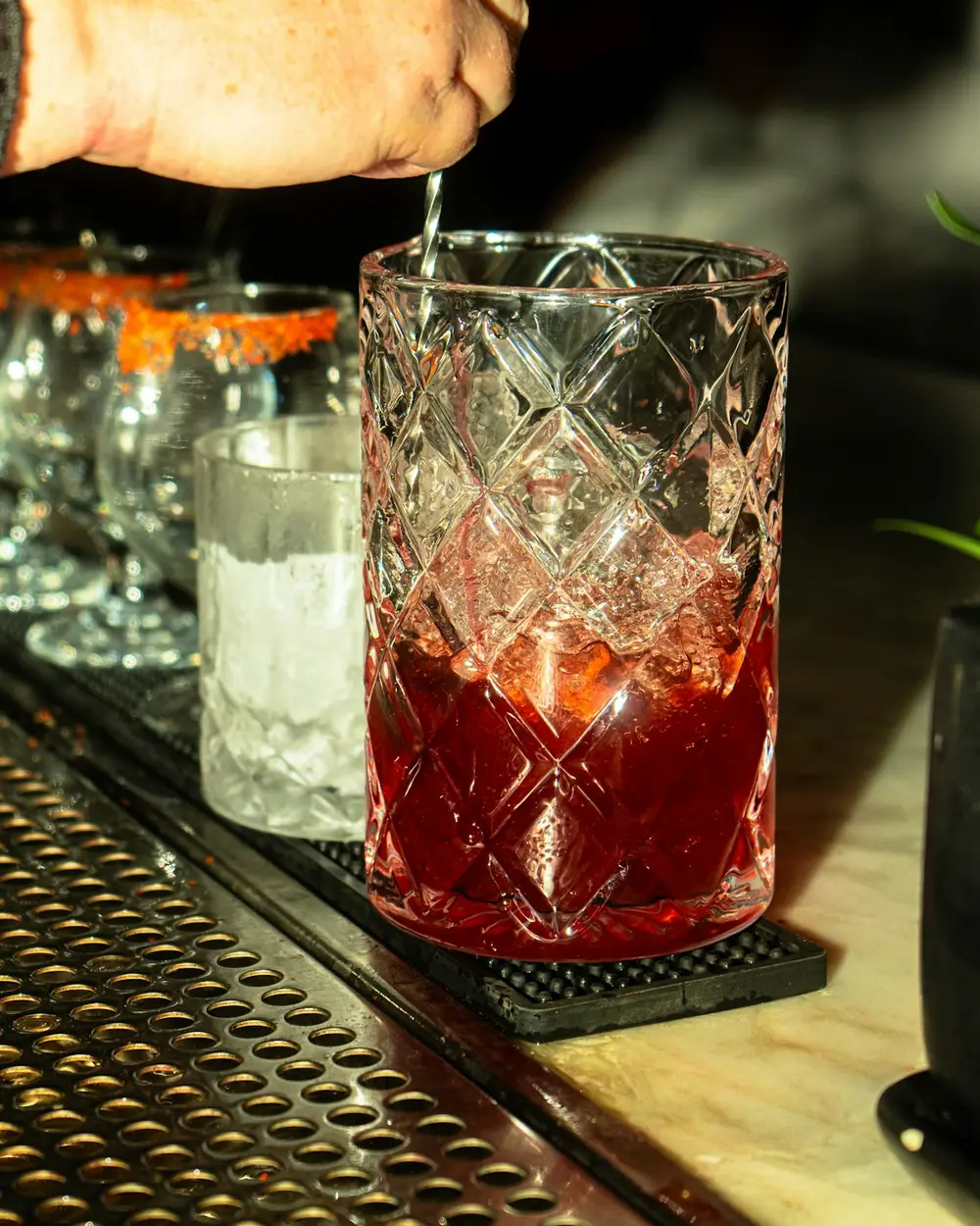 A bartender stirs a cocktail in a mixing glass