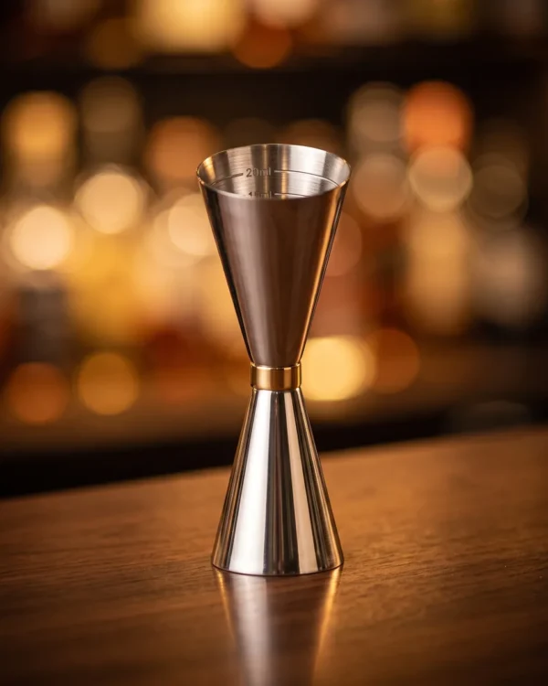 Jigger 30/60 ml stainless steel, gold ring, on a bar counter